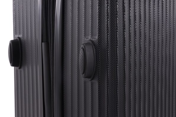 Close-up of a black textured suitcase surface with protruding circular bumpers on the side.